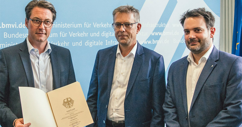Verkehrsminister Andreas Scheuer (CSU) überreicht den Förderbescheid an die KoelnMesse-Manager Georg Klumpe und Gert Messerschmidt (Foto: KoelnMesse)